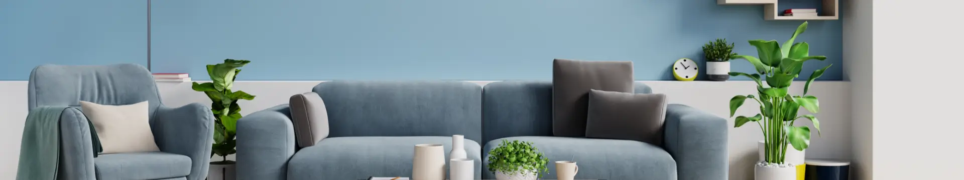 Sala de estar moderna com parede azul de fundo, sofá e poltrona em tom azul-claro, almofadas decorativas, mesa de centro e diversos vasos de plantas